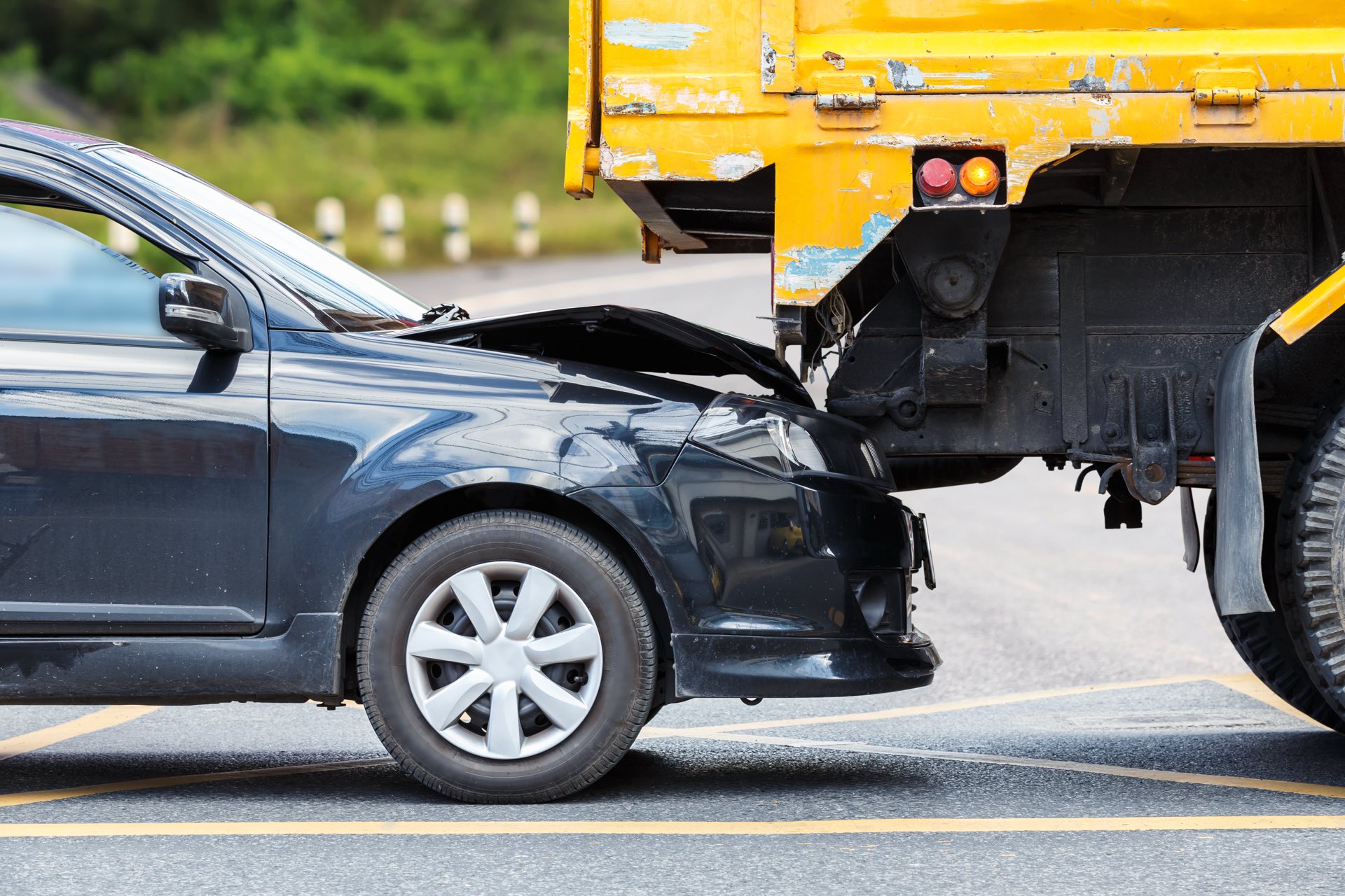 A black car wrecked into the back of a yellow truck