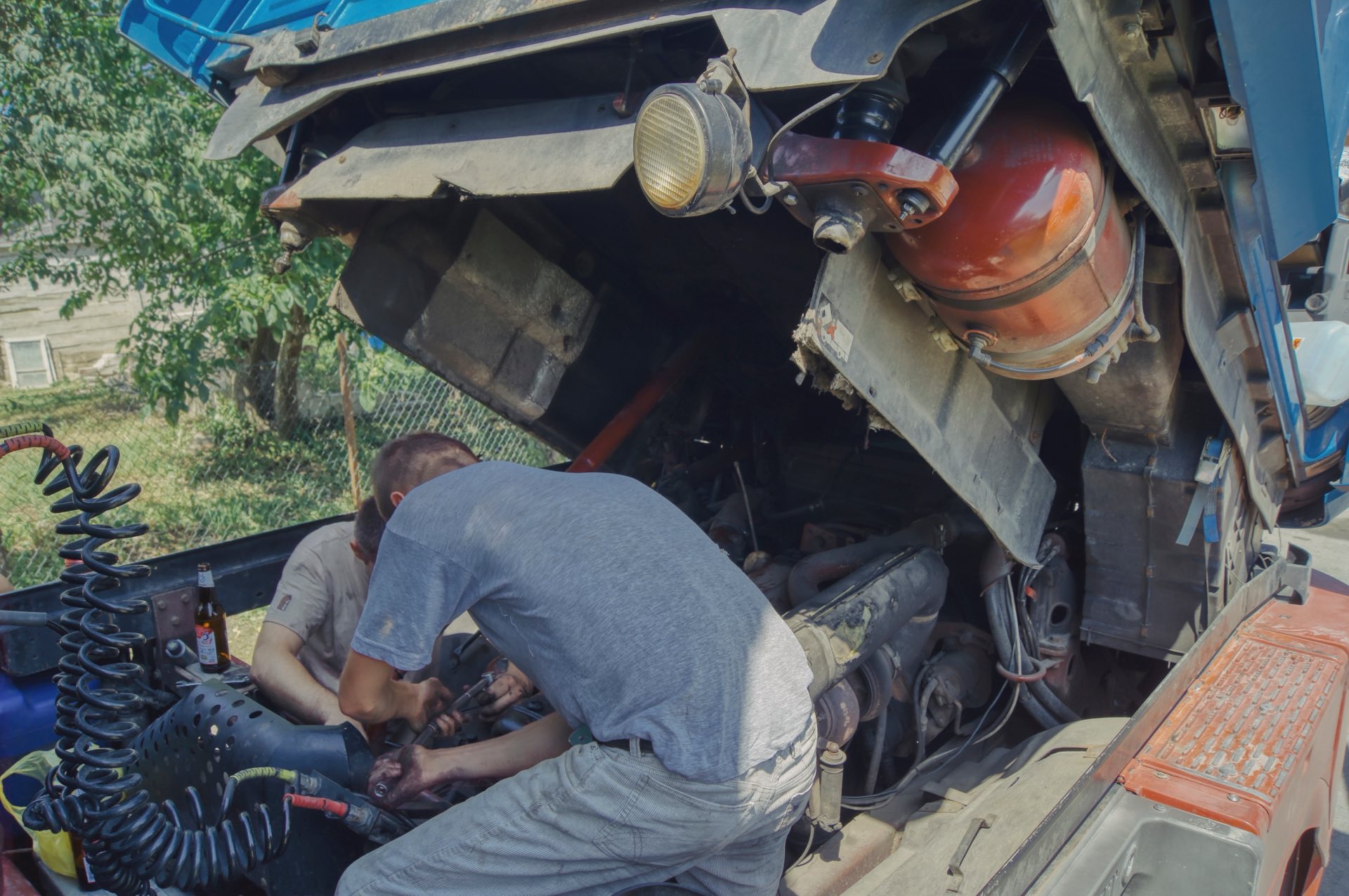 Two people working under a trucks hood