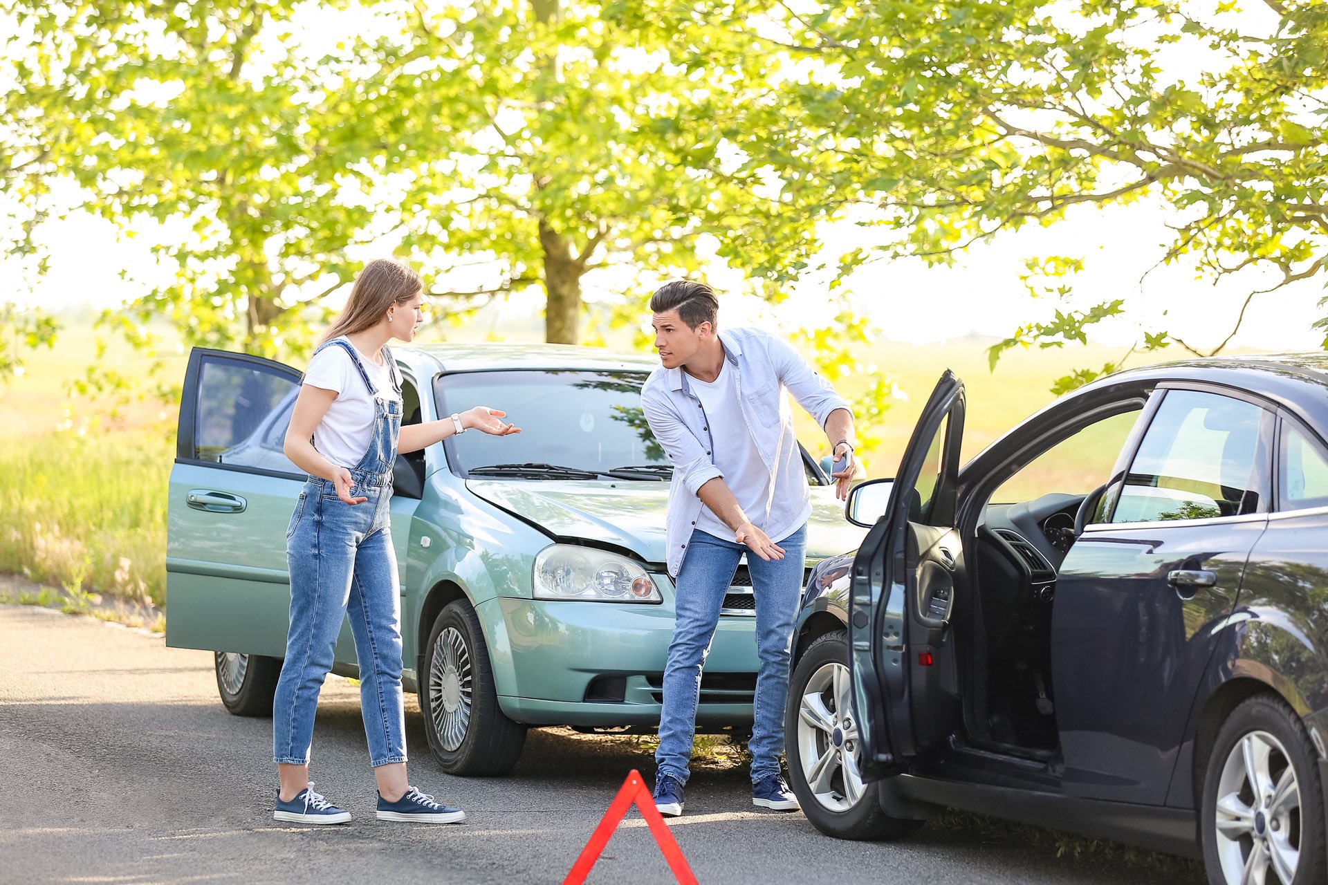 Two stressed drivers near what looks like a car accident talking