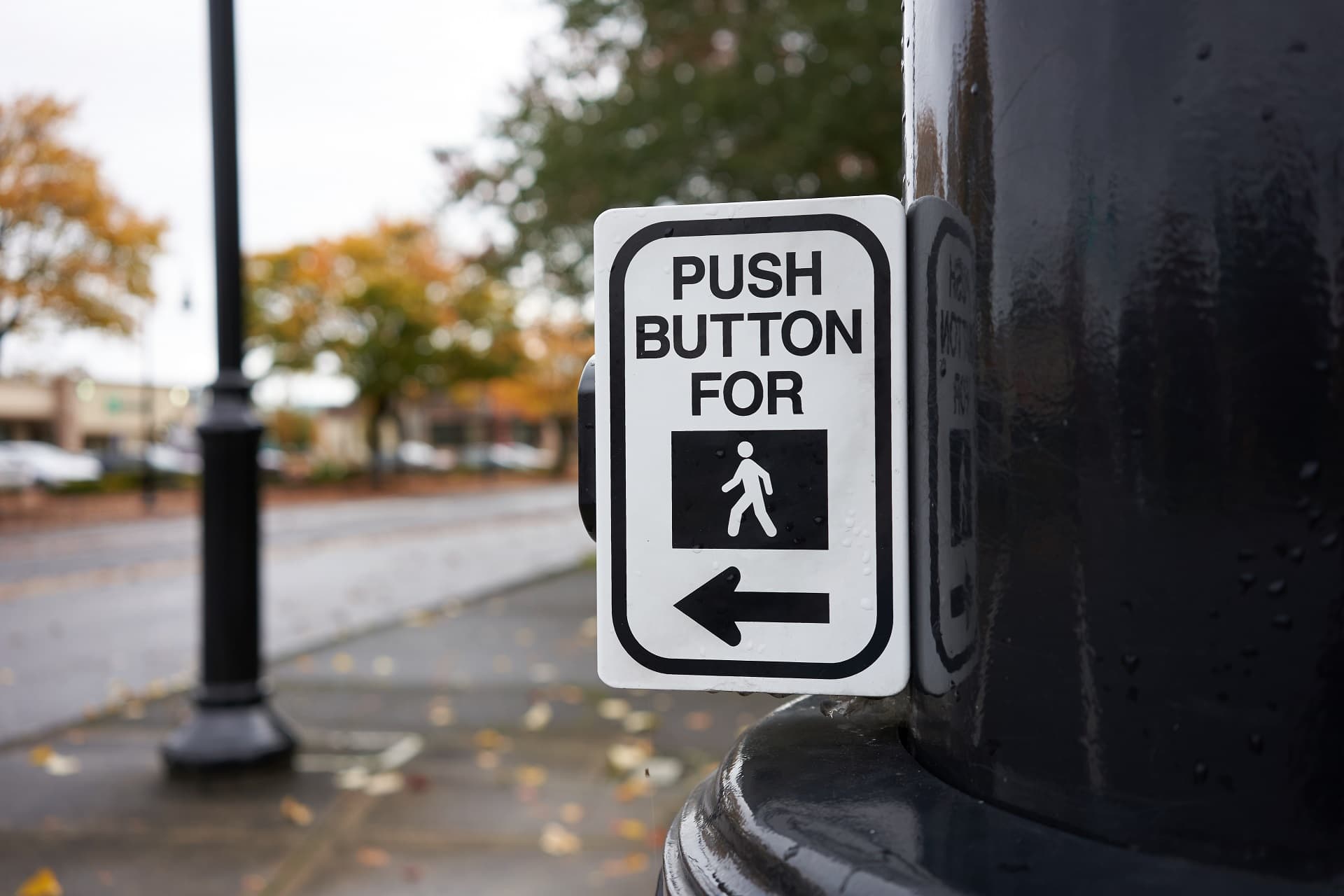 Push button for walk signal sign attached to a post on a city st