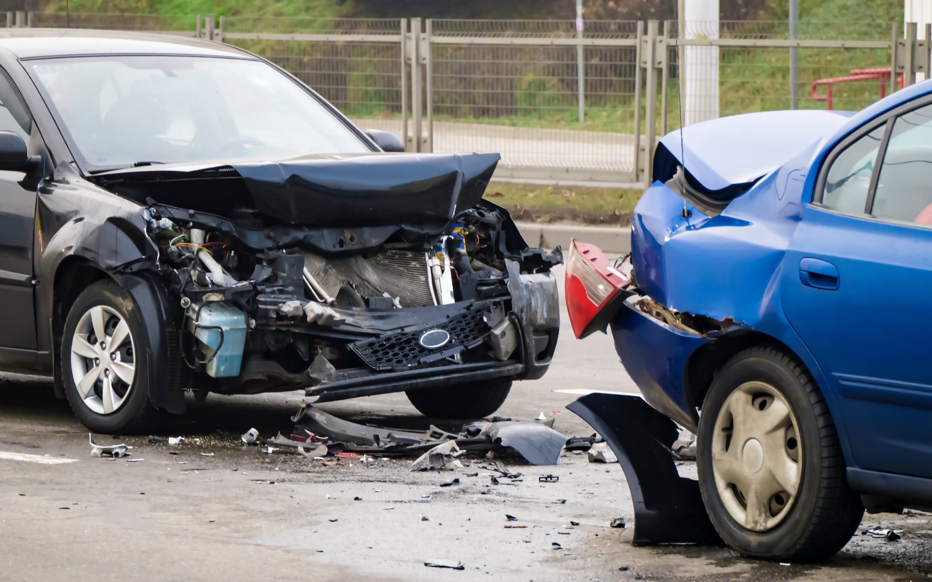 Side view. Front of dark and back of blue cars damaged and broken by accident on the road