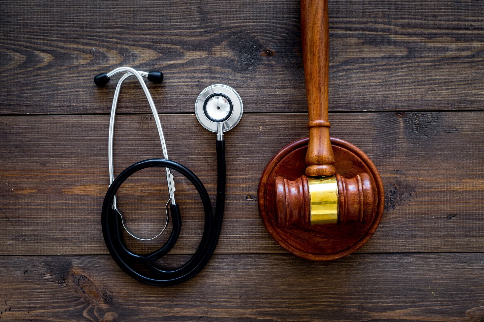 Medical law, health law concept. Gavel and stethoscope on dark wooden backgound top view