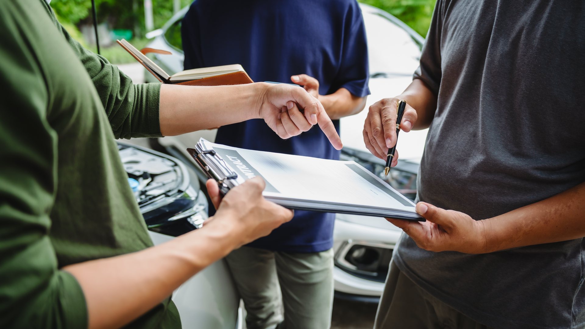 Three people discussing insurance paperwork on a clipboard