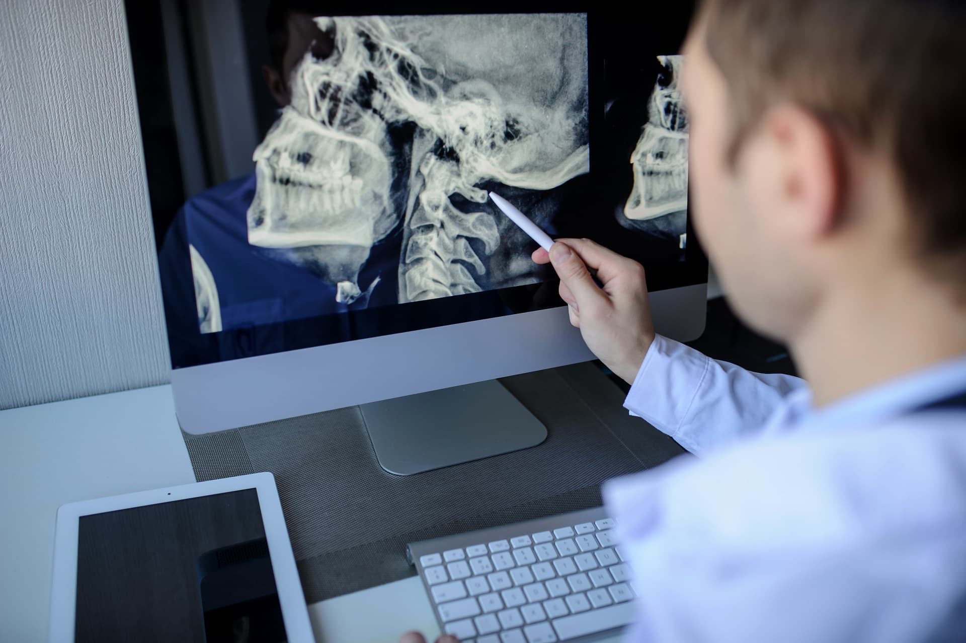 back view of a male radiologist examining neck x-rays (cervical