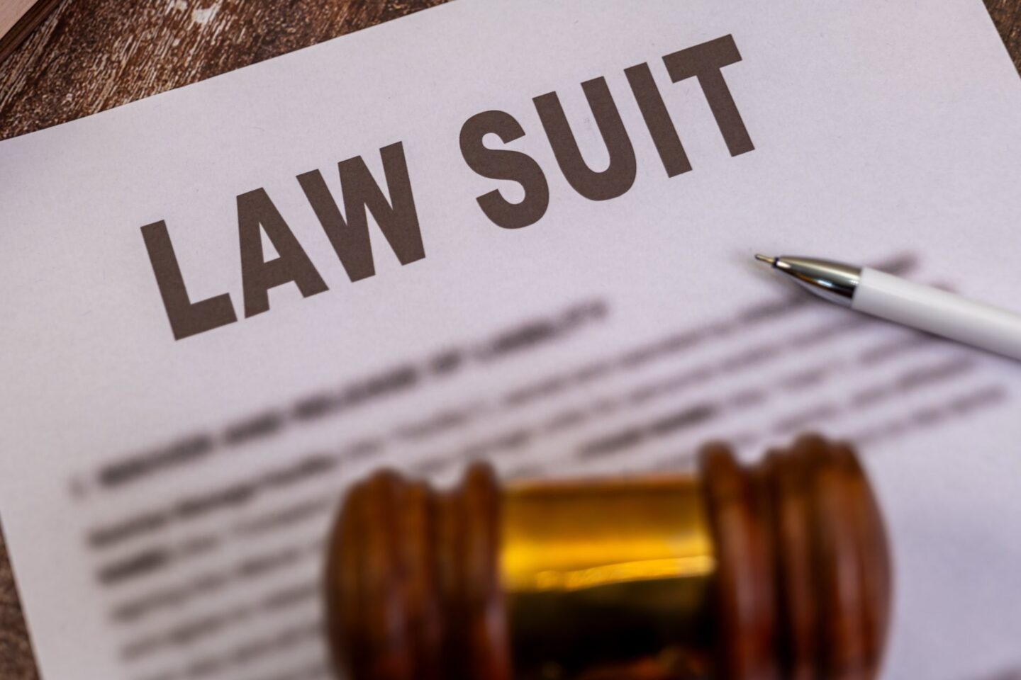 Legal document that says law suit, gavel, and a pen on desk
