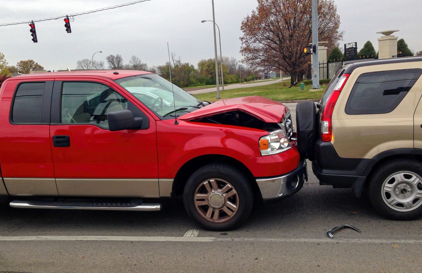 Red truck rear-end collision with brown SUV resulting in bent hood on truck
