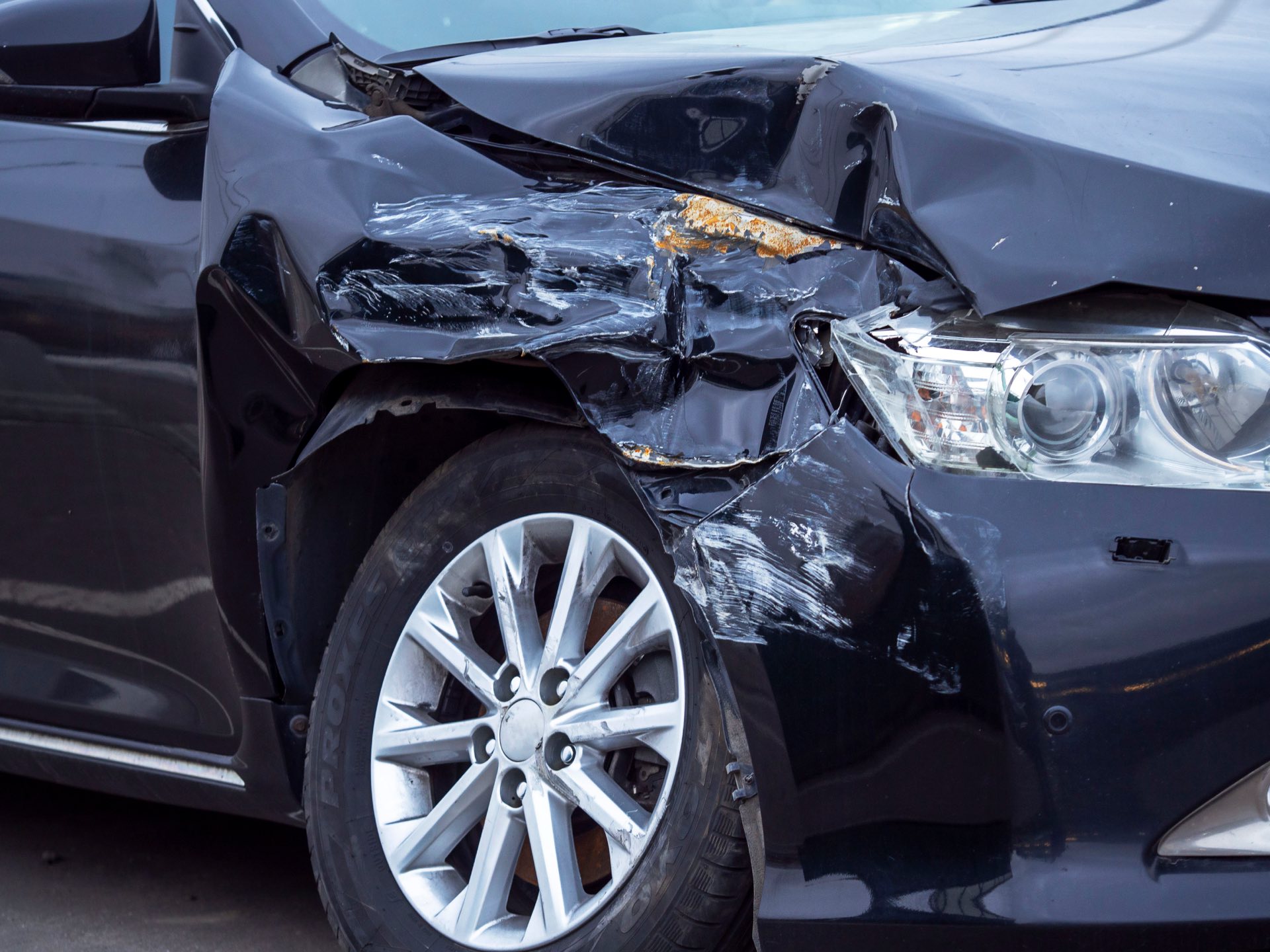 Close up photo of a black car with damage to front right fender