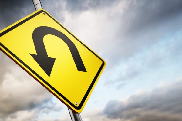 U turn road warning sign against a gloomy sky