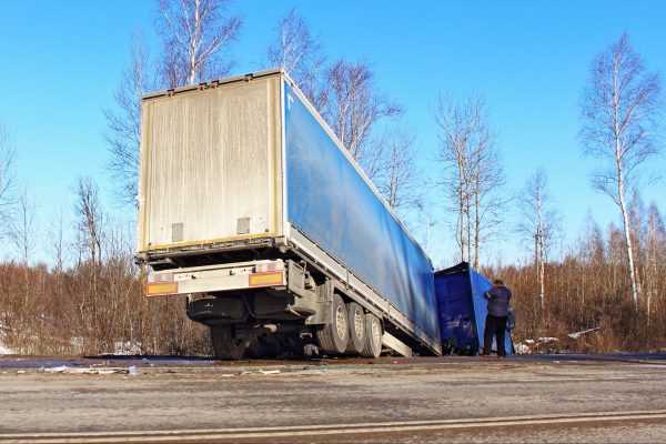 Semi truck wrecked in a ditch surrounded by trees