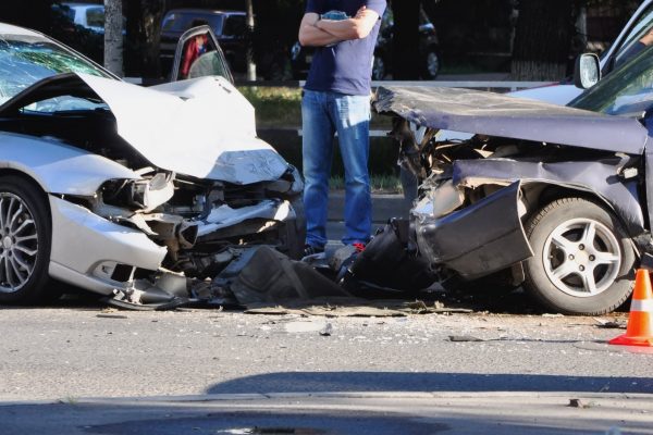 Two cars involved in a car accident with a person standing in between both cars