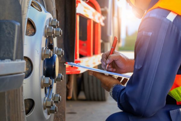 Mechanic checking truck wheel maintenance | truck accident lawyer | Henderson Taylor Law Firm